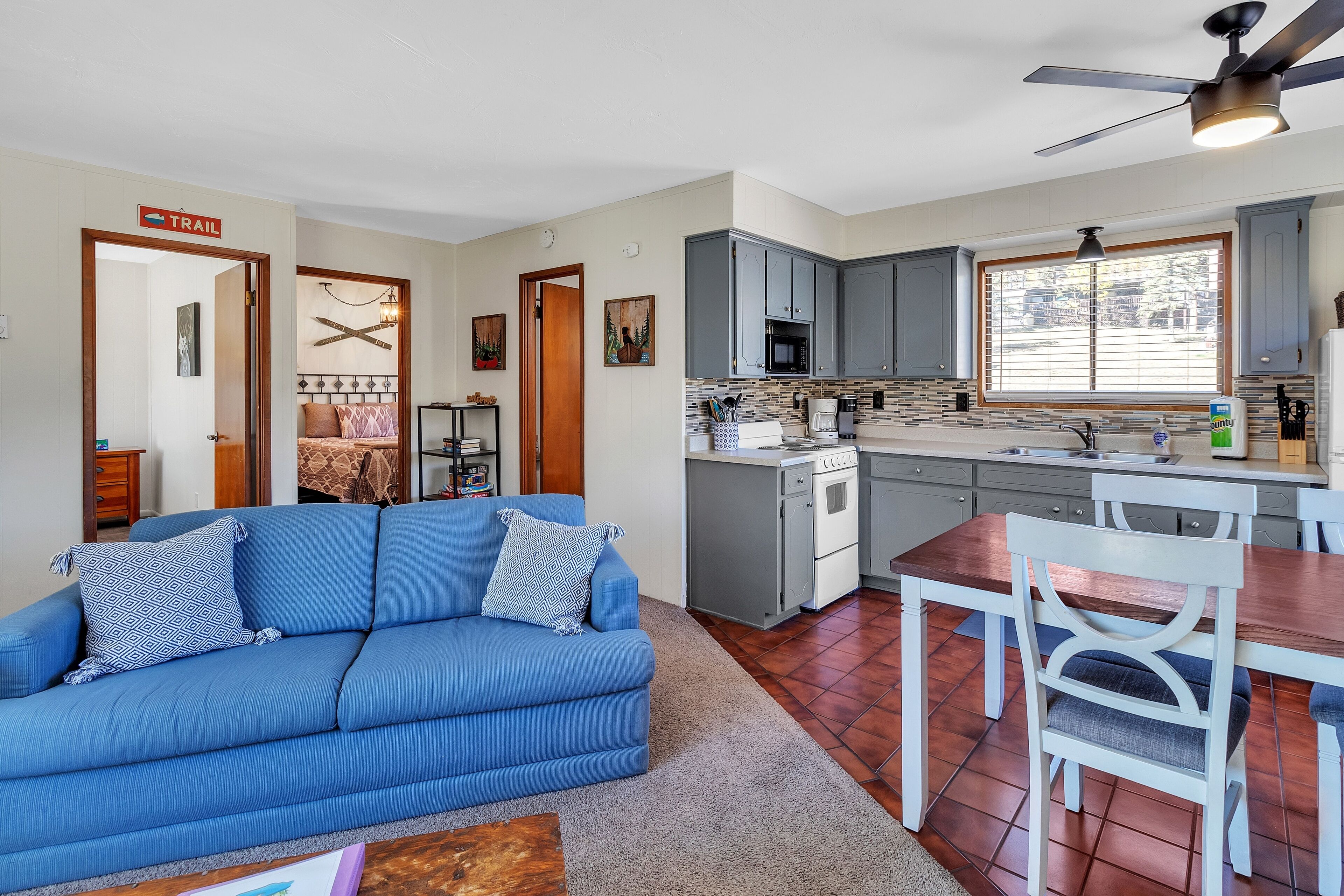 A compact living space with a kitchenette, a dining area, and a sofa with patterned cushions.