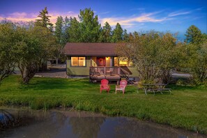A lodge with a deck, two red Adirondack chairs, and a picnic table. - Cozy Cabin Retreat With Scenic Views 2 Bedroom Cabin (Greer)