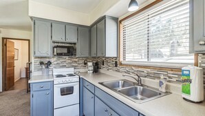 A kitchen with blue cabinets, a white stove, a microwave, and a sink. - Cozy Cabin Retreat With Scenic Views 2 Bedroom Cabin (Greer)