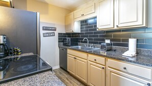 A kitchen with a black tiled backsplash, a stainless steel refrigerator, a built-in oven, and beige cabinetry. - E108 W Beaver Creek Blvd 2 Bedroom Condo (Avon)
