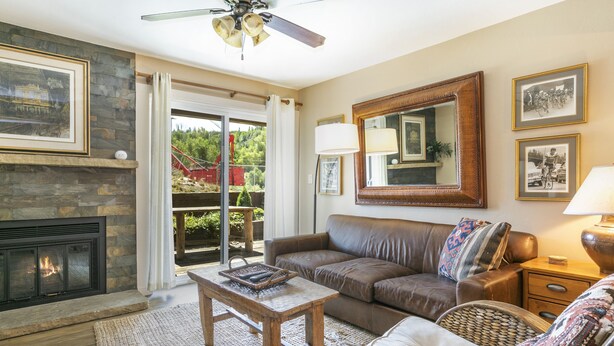 A living room with a fireplace, a sofa, a coffee table, and a large mirror. - E108 W Beaver Creek Blvd 2 Bedroom Condo (Avon)