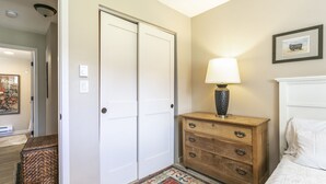A bedroom with a bed, a dresser, a lamp, a rug, and a door. - E108 W Beaver Creek Blvd 2 Bedroom Condo (Avon)