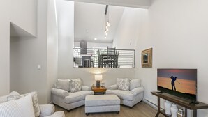 Una sala de estar moderna con dos sofás, una mesa de centro y un televisor sobre un mueble de madera.