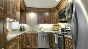 A modern kitchen with wooden cabinets, stainless steel appliances, and a tiled backsplash. - Valley Condos A25 3 Bedroom Condo (Vail)