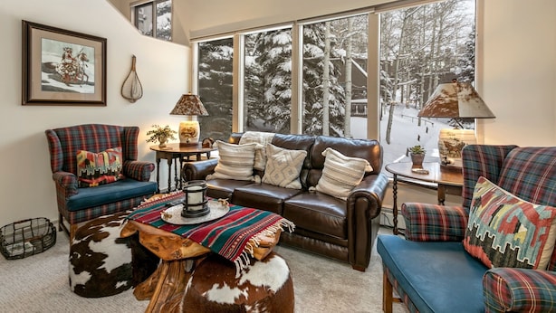 A cozy living room with a leather sofa, plaid armchairs, and a wooden coffee table. - Valley Condos A25 3 Bedroom Condo (Vail)