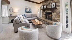 Ein gemütliches Wohnzimmer mit Kamin aus Stein, einem grauen Ecksofa und zwei Zierteilen.