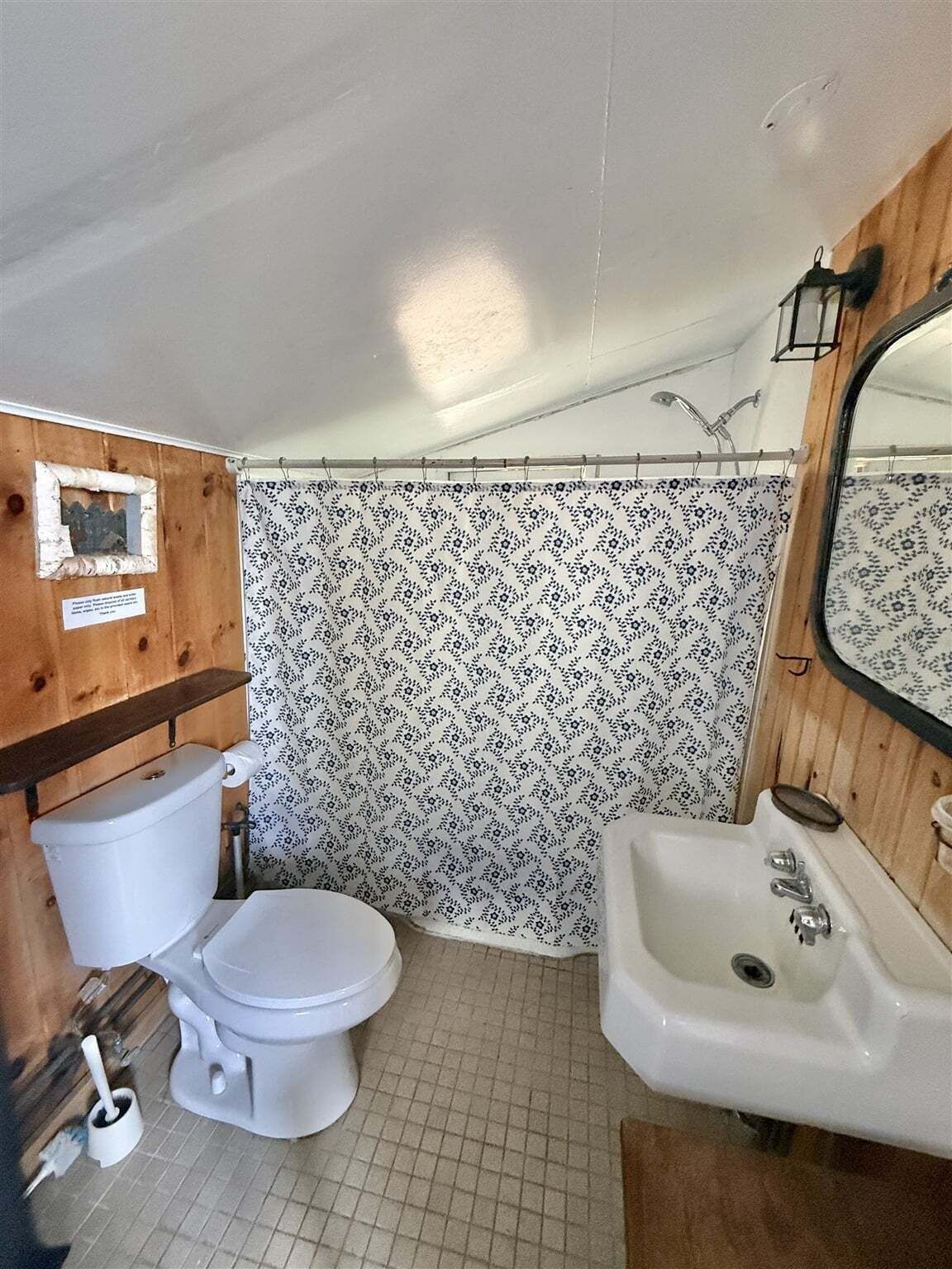 A compact bathroom with a toilet, sink, and shower.