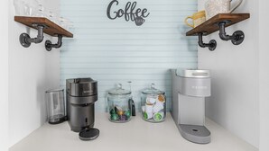 Eine Kaffeestation mit einer Kaffeemaschine, einer Kaffeemühle und zwei Glasbehältern für Kaffeekapseln.