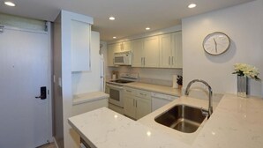 Una cocina moderna con armarios blancos, electrodomésticos de acero inoxidable y encimera de mármol.