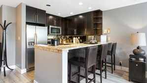 A modern kitchen with dark cabinets, stainless steel appliances, and a granite countertop. - Simba Run 1525 2 Bedroom Condo (Vail)