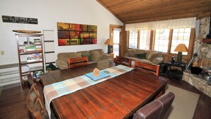 Ein geräumiges Wohnzimmer mit einem Holzespeisetisch, bequemen Sofas und einem Kamin aus Stein.