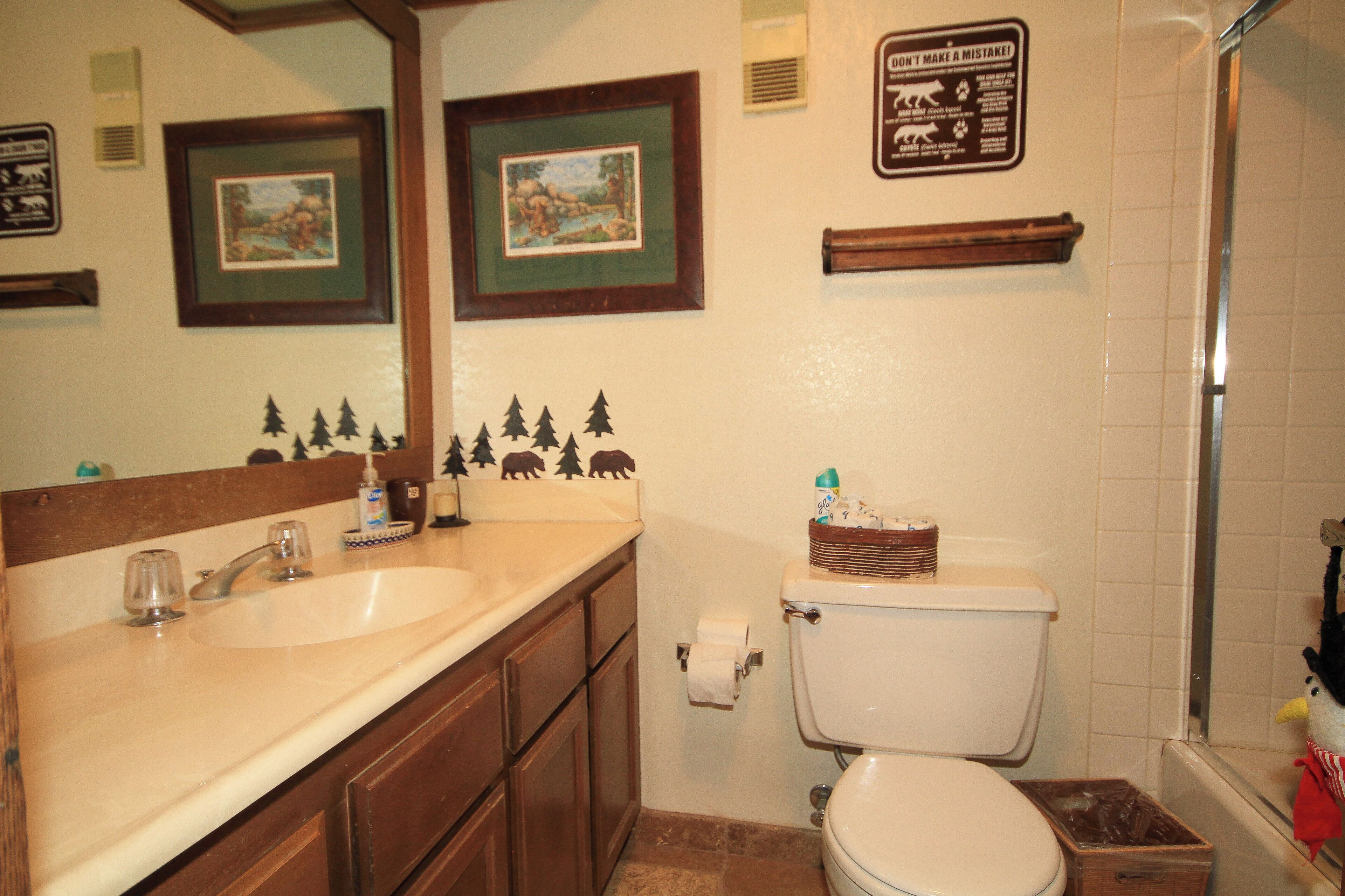 A bathroom with a sink, mirror, toilet, and shower.
