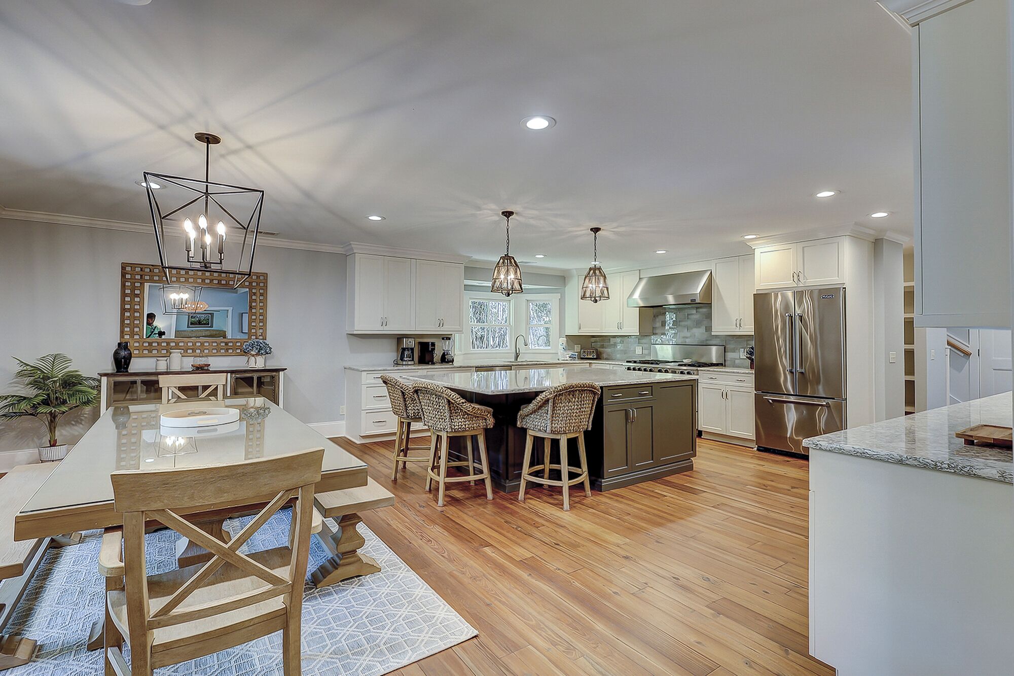 A modern kitchen with a central island, bar stools, and stainless steel appliances.