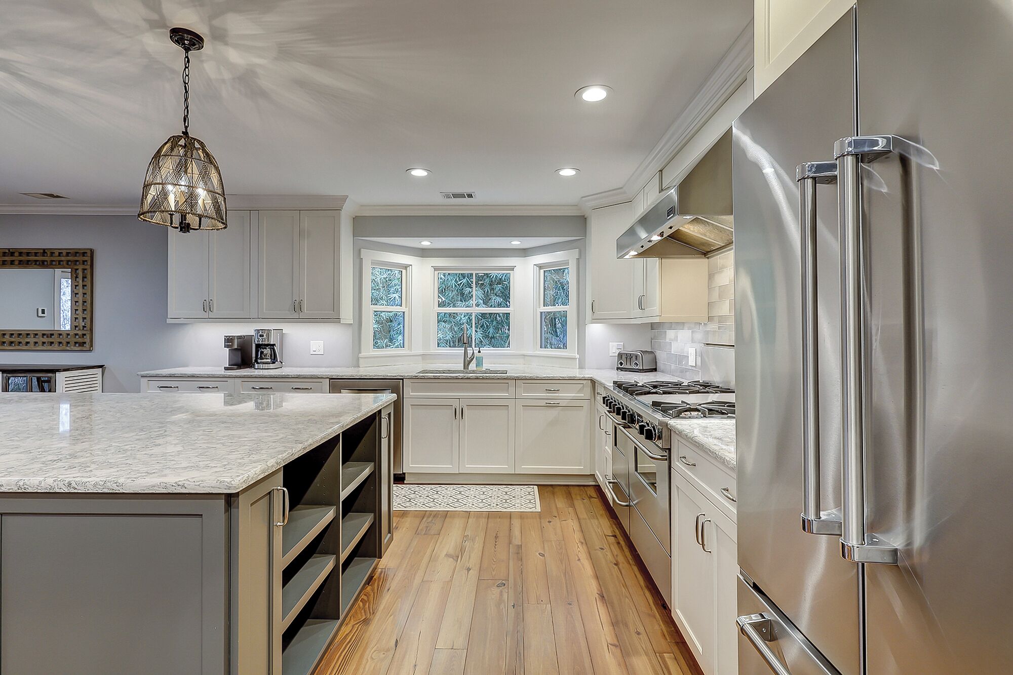 A modern kitchen with a central island, stainless steel appliances, and a large window providing natural light.
