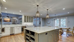 A spacious kitchen with a large island, wooden flooring, and pendant lighting. - 58 Heritage Road - Harbour Town Golf Course Views & a Short Walk to the Beach (Hilton Head Island)