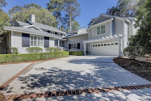 A two-story house with a garage, a covered driveway, and a well-maintained lawn.