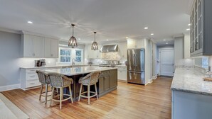 A modern kitchen with a large island, stainless steel appliances, and a wooden floor. - 58 Heritage Road - Harbour Town Golf Course Views & a Short Walk to the Beach (Hilton Head Island)