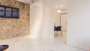 A hallway with a stone wall, a flat-screen TV mounted on it, and a dining area with a table and chairs in the background. - Residence Piccolo Lord 2 - Italian Homing (Calcinato)