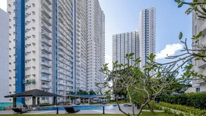 Een hoog appartementencomplex met meerdere balkons, een zwembad en een overdekt terras.