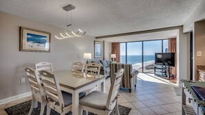 Ein Essbereich mit Tisch und Stühlen, einem Fernseher und Blick auf den Ozean.