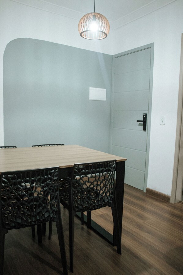 A dining area with a wooden table and black chairs, a light fixture above, and a door with a handle.