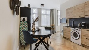Eine moderne Küche mit Holzausstattung, einer integrierten Waschmaschine und einem Essbereich mit rundem Tisch und Stühlen.