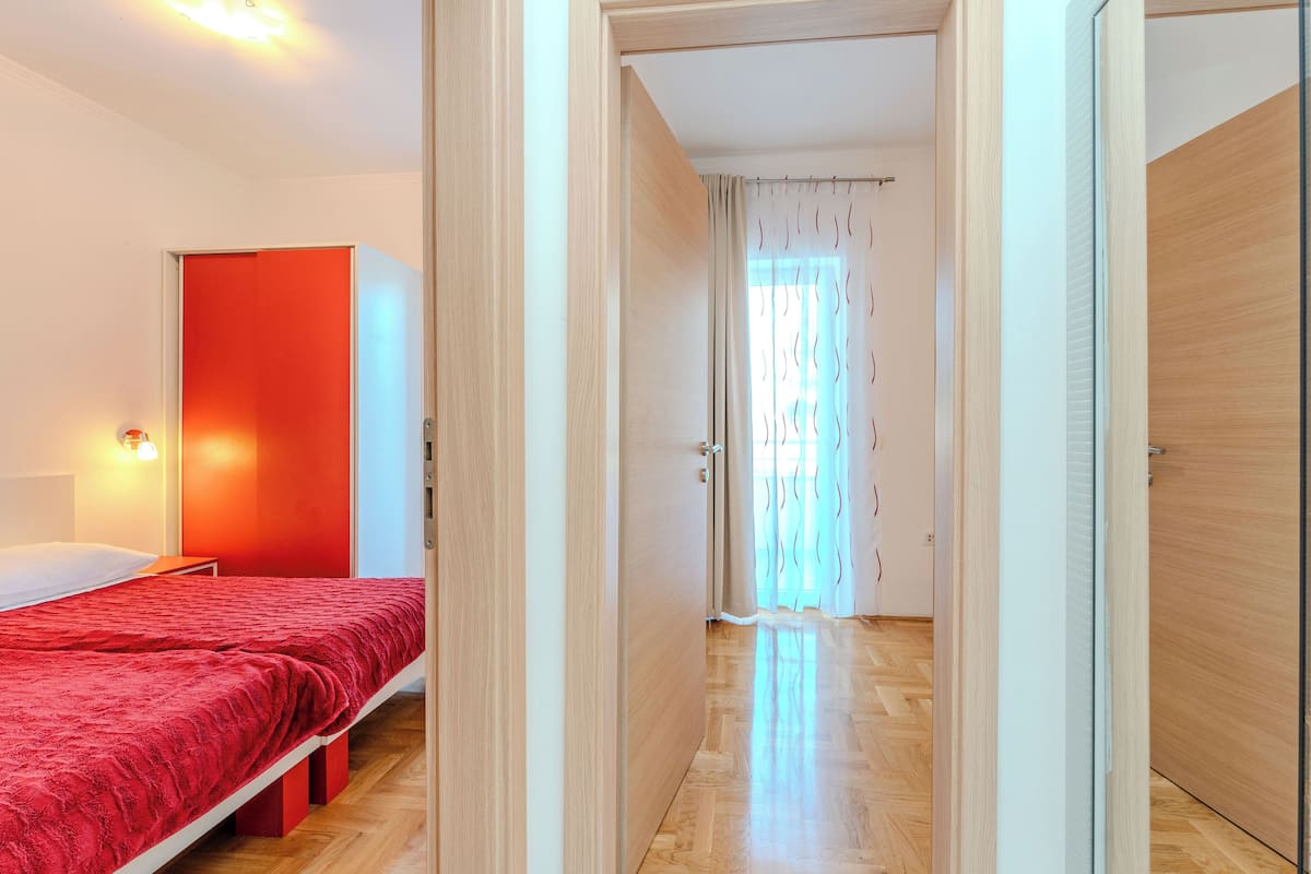 A bedroom with a red bedspread, a bedside lamp, and a wardrobe.