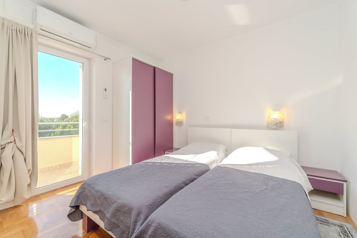 A bedroom with a bed, a nightstand, a wardrobe, and a sliding glass door leading to an outdoor area.