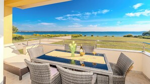 Een balkon met een tafel en stoelen, met uitzicht op de kust.
