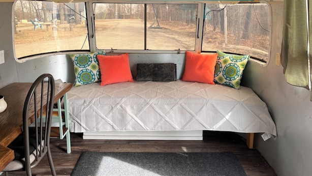 Un ambiente acogedor con una cama, una mesita y una ventana que da a un bosque.