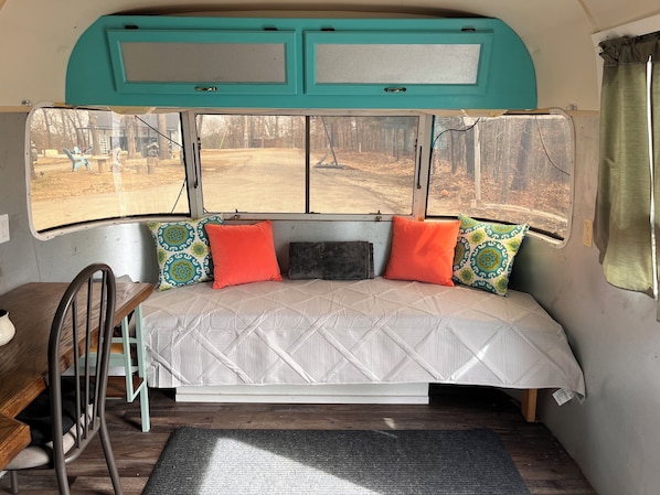 Een gezellig interieur met een bed, een klein tafeltje en een raam met uitzicht op een bos.