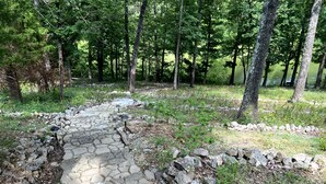 A stone pathway in a wooded area with trees and a clear sky. - Cozy Home - Fire Pit - Seasonal Fishing (Williford)