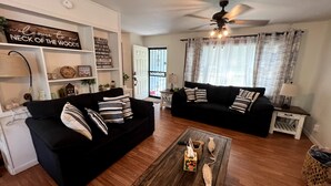 A living room with two black sofas, a wooden coffee table, and a ceiling fan. - Cozy Home - Fire Pit - Seasonal Fishing (Williford)
