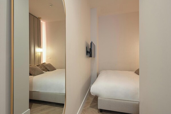 A bedroom with a bed, bedside table, and a wall-mounted TV. - Novallure Downtown (The Hague)