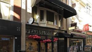 A building with a storefront labeled "Tattoo Frog" and a sign for "Novallure Downtown Short Stay Apartments" above. - Novallure Downtown (The Hague)