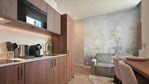 A modern kitchen with wooden cabinets, a built-in oven, and a coffee machine. - Novallure Downtown (The Hague)