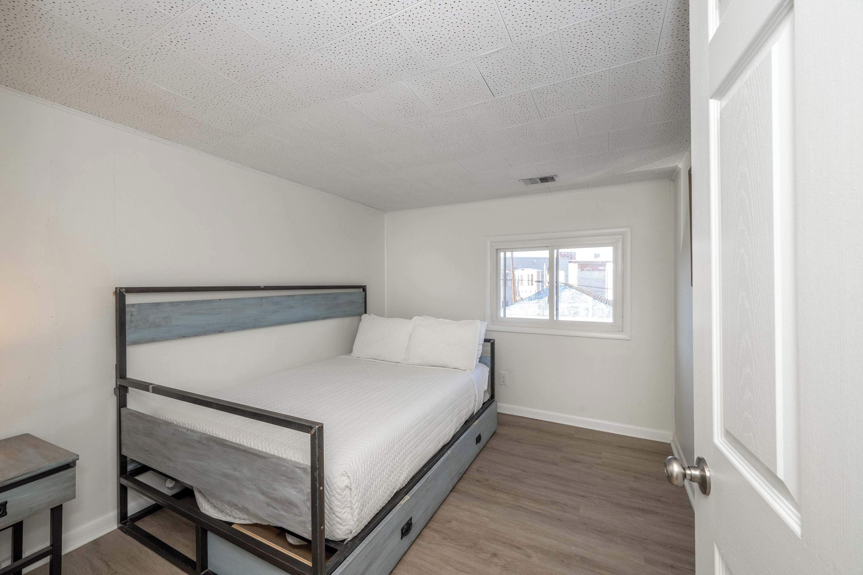 A bedroom with a bed, a small table, and a window.