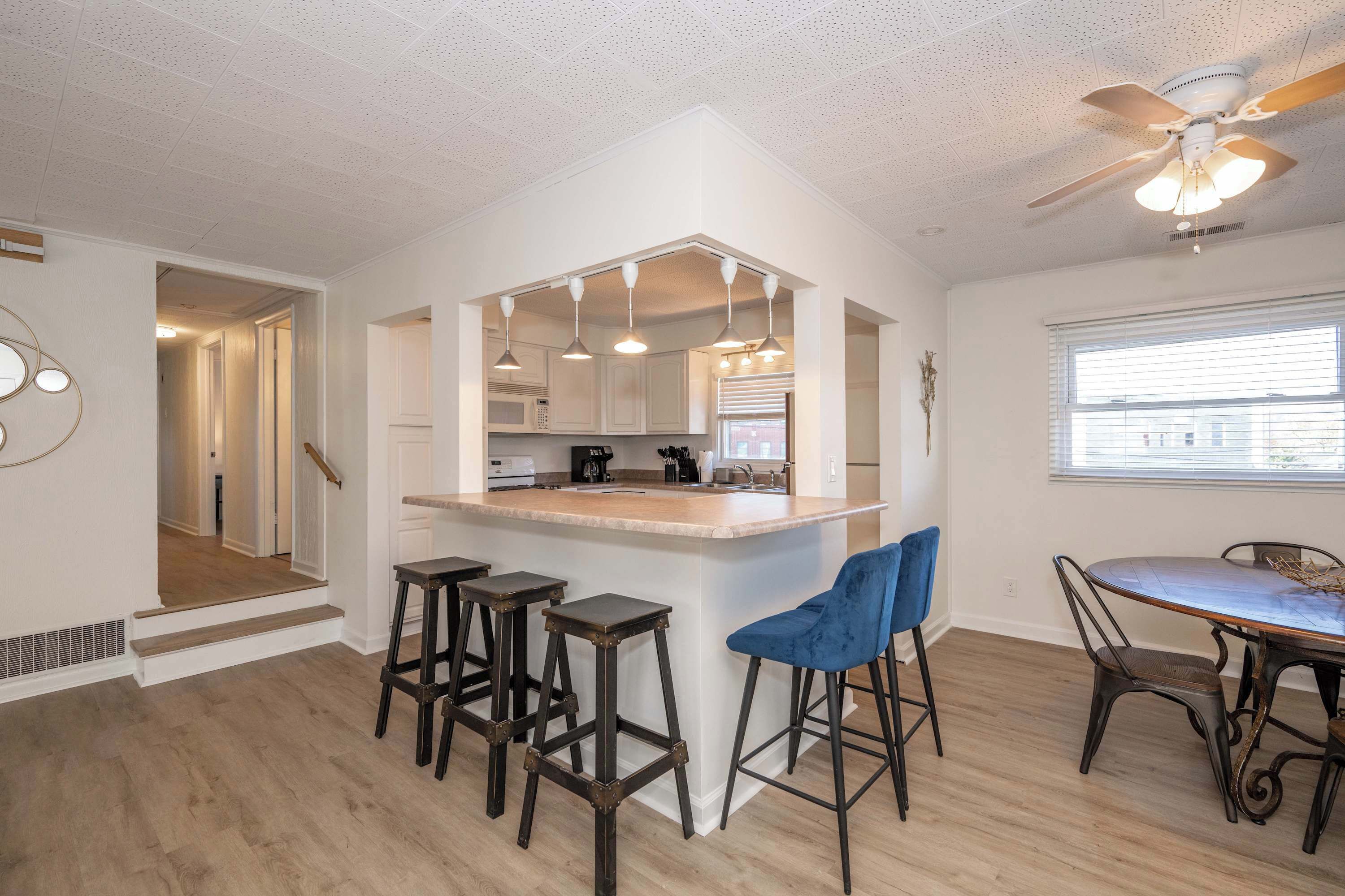 A modern kitchen with a central island, bar stools, and a dining table with chairs.