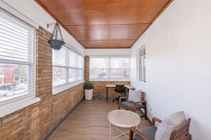 Un rincón acogedor con pared de ladrillo, techo de madera y una pequeña mesa con sillas.