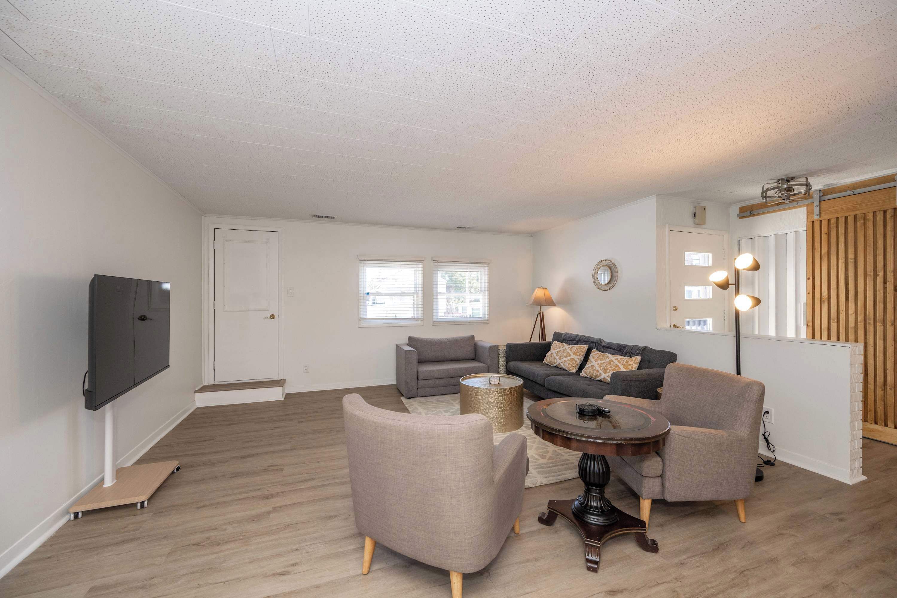 A living room with a flat-screen TV, two grey sofas, a coffee table, and a lamp.
