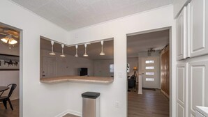 A modern kitchen with a wooden countertop, a trash can, and pendant lighting. - The Grand Elm Suite 2 (Ludlow)