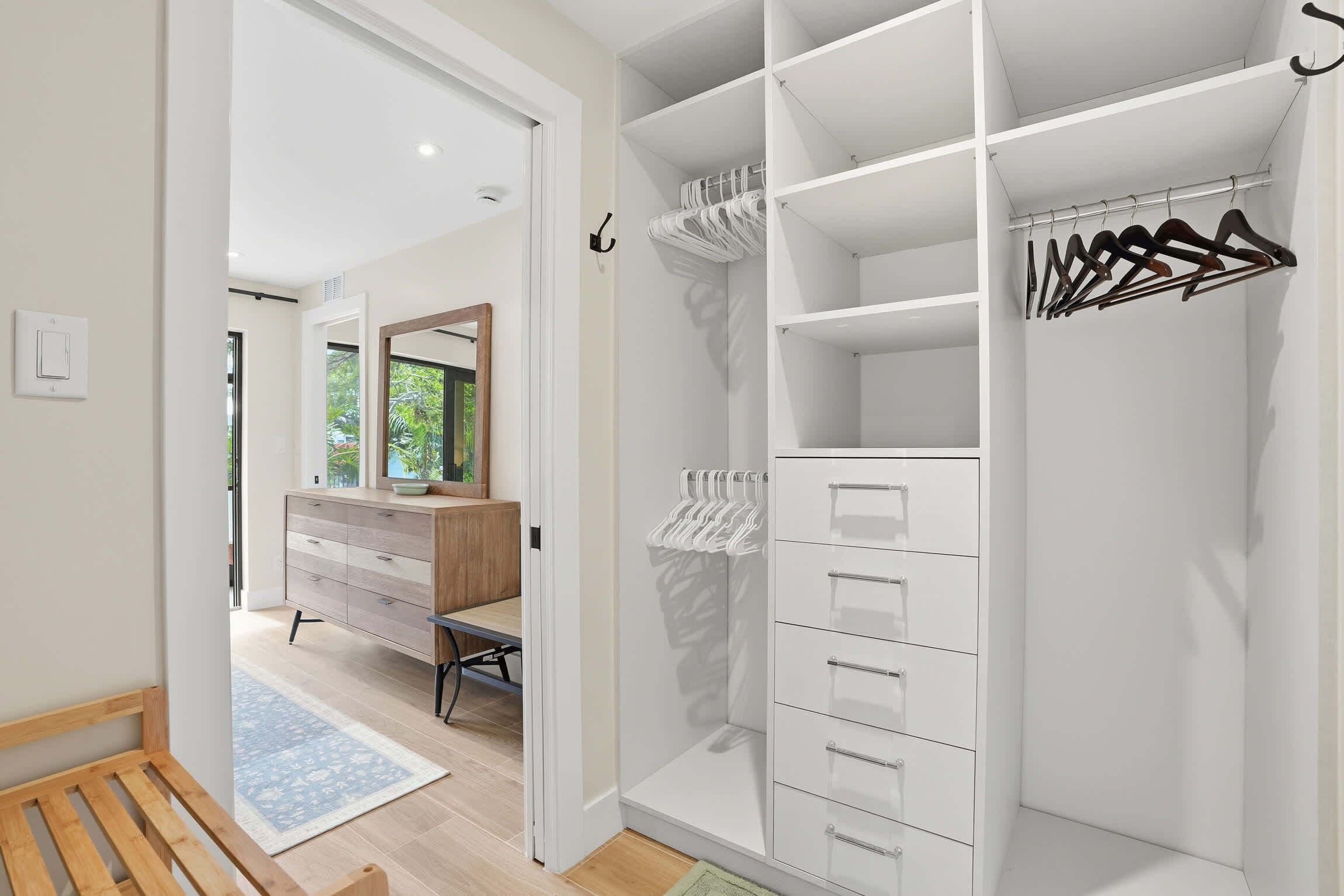 A walk-in closet with open shelves, hanging space, and drawers.
