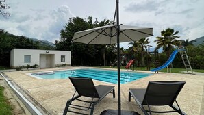 A poolside area with two lounge chairs, a table, and a large umbrella.