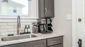 Una cocina con encimera de granito, cafetera y lavamanos.