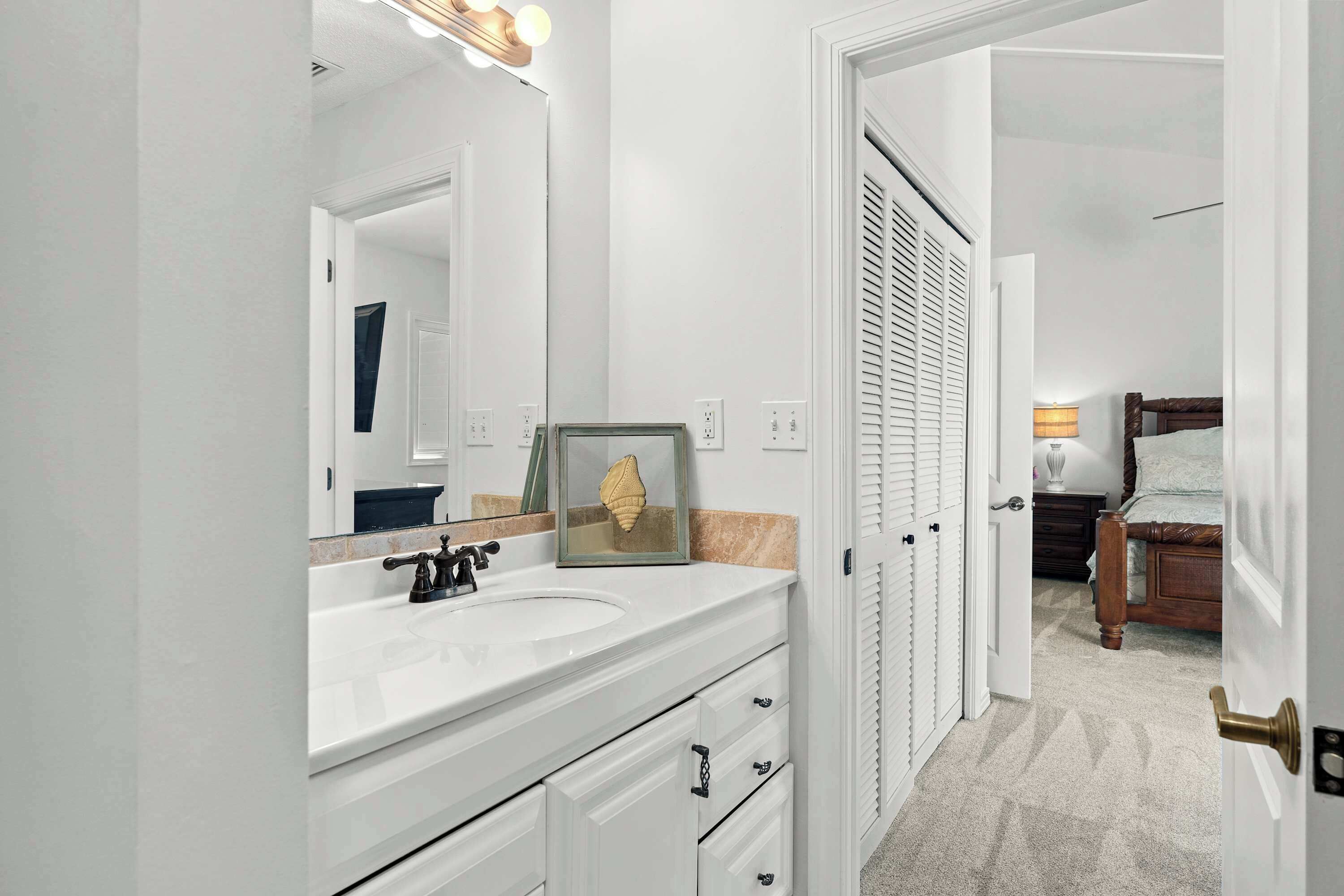 Une salle de bain moderne avec un meuble-lavabo blanc, un grand miroir et un tableau encadré.