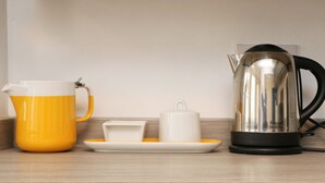 A kitchen counter with a yellow pitcher, a white cup, a white saucer, and a black electric kettle. - Town centre apartment with parking- Dog friendly! (Padstow)