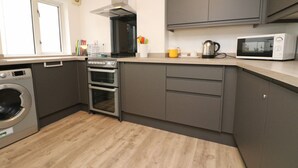 A modern kitchen with a built-in oven, microwave, and stainless steel range hood. - Town centre apartment with parking- Dog friendly! (Padstow)