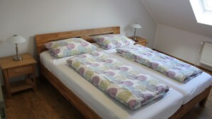 A double bed with a wooden headboard, two bedside tables with lamps, and a skylight above. - Vacation apartment Molly (Brunsbüttel)