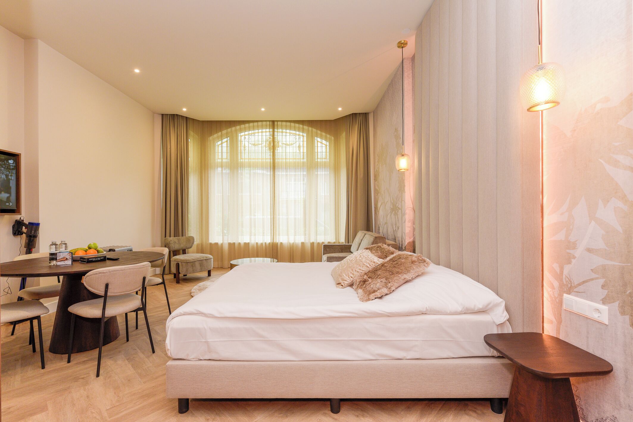 Ein Hotelzimmer mit Bett, Schreibtisch, Stühlen und Esstisch.