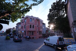 A cobblestone street with a pink building, a white van, and a blue signboard. - Keeper  (Istanbul)
